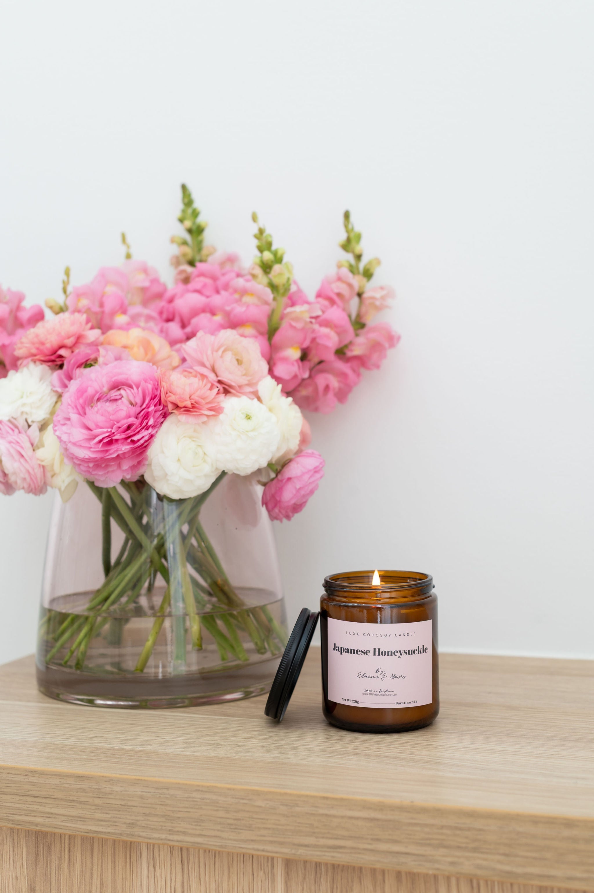 Soy Candle and vase with flowers on a wooden surface