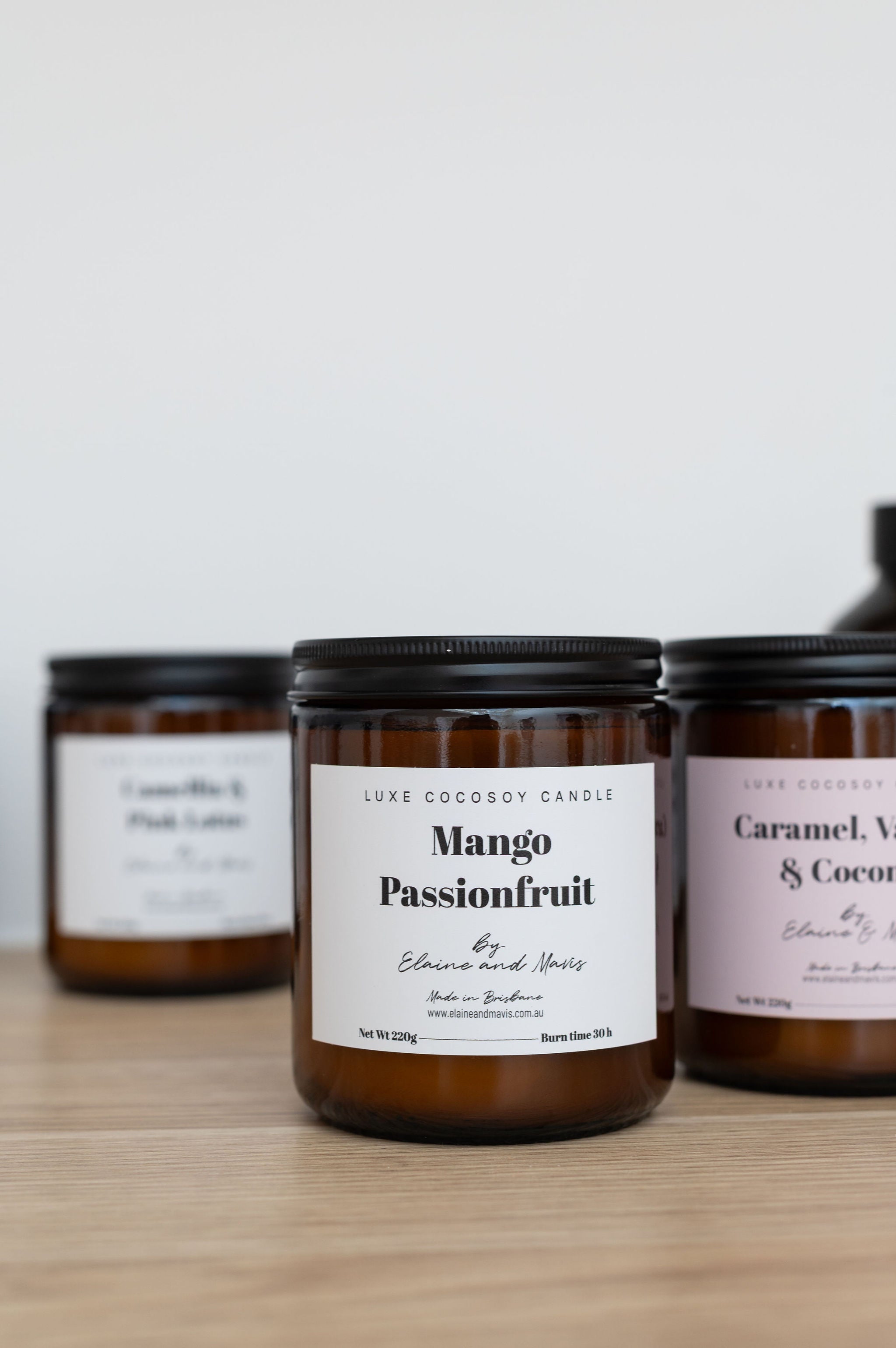 Mango & Passionfruit Candle jars with labels on a wooden surface