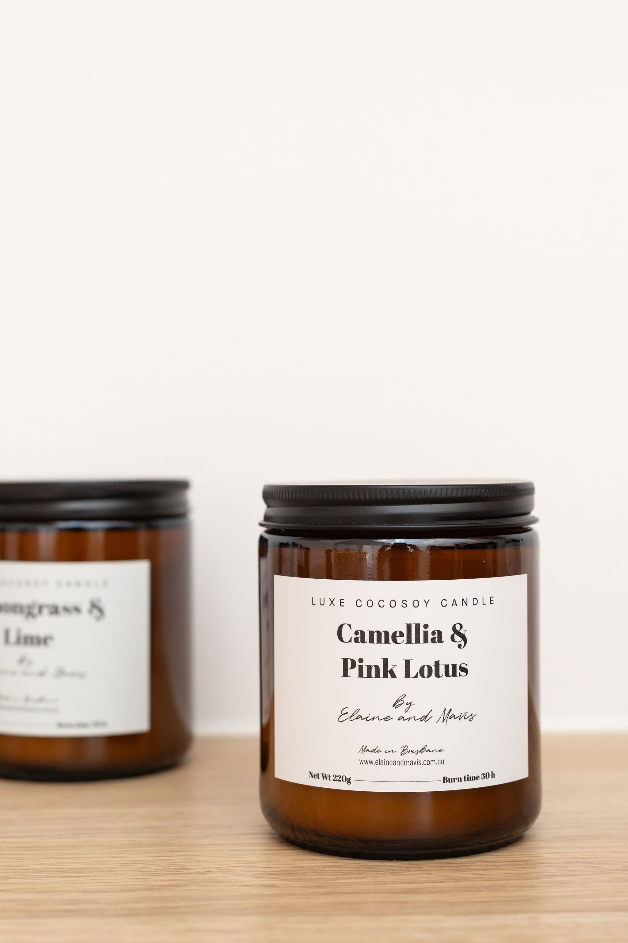 Camelia and Pink Lotus candle with labels on a wooden surface